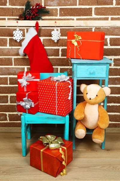 ख्रिसमस तपकिरी वीट भिंत पार्श्वभूमीवर खुर्चीवर सादर — स्टॉक फोटो, इमेज