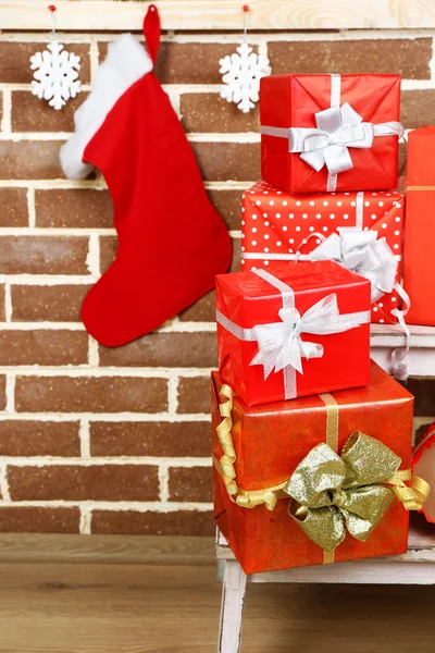 Regalos de Navidad en escalera de pie sobre fondo de pared de ladrillo marrón — Foto de Stock
