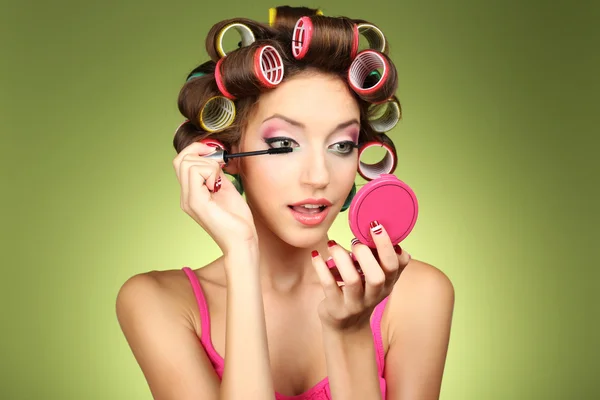 Beautiful girl in hair curlers on green background — Stock Photo, Image