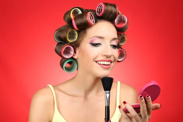 Hermosa chica en rulos de pelo sobre fondo rojo —  Fotos de Stock