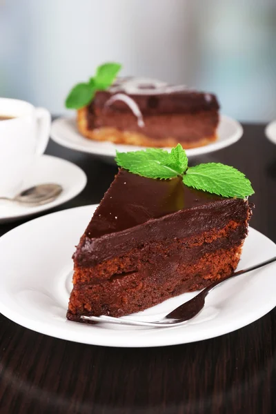 Trozos de pastel de chocolate en platos y taza de té en mesa de madera sobre fondo natural — Foto de Stock