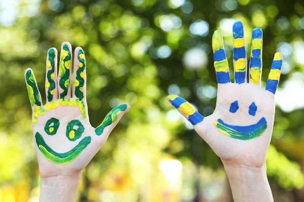 Smiling colorful hands on natural background — Stock Photo, Image