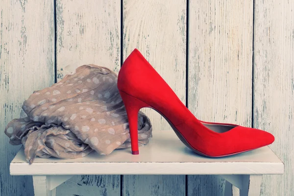 Red women shoes and scarf on bench on wooden background — Stock Photo, Image