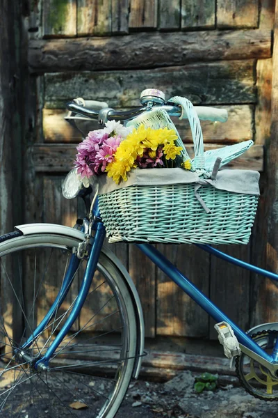 Vieux vélo avec des fleurs dans un panier en métal sur fond de vieille porte marron — Photo