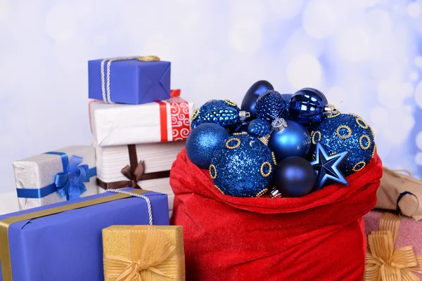 Sac rouge avec jouets de Noël et cadeaux sur fond lumineux — Photo