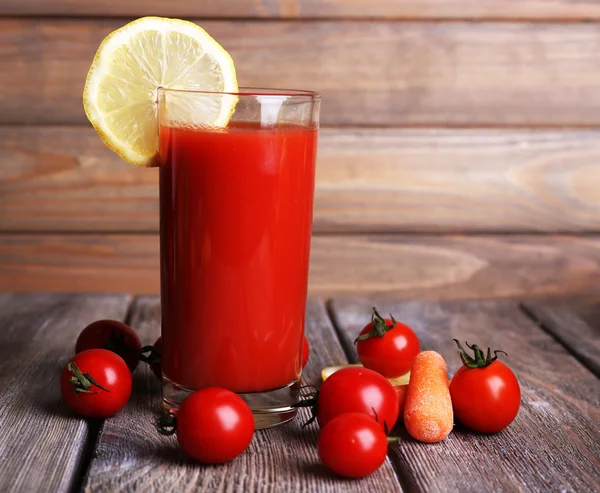 Szklankę soku pomidorowego z cytryny i świeżych pomidorów na drewnianym stole na tle ściany drewniane — Zdjęcie stockowe