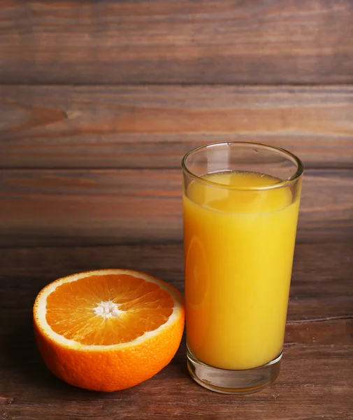 Glas apelsinjuice och färska orange på träbord på trävägg bakgrund — Stockfoto