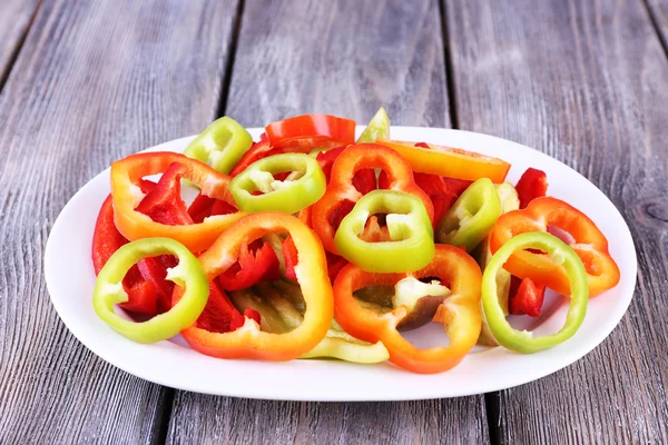 Sliced pepper on oval plate on wooden background — Stock Photo, Image