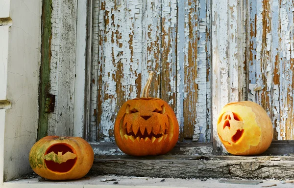Tatil eski ahşap kapı arka plan üzerinde Halloween kabaklar — Stok fotoğraf