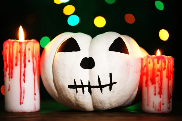 Halloween white pumpkin and candle on table on dark color background with multicolor lights — Stock Photo, Image