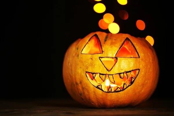 Хэллоуин тыква на столе на темном фоне цвета с разноцветными огнями — стоковое фото