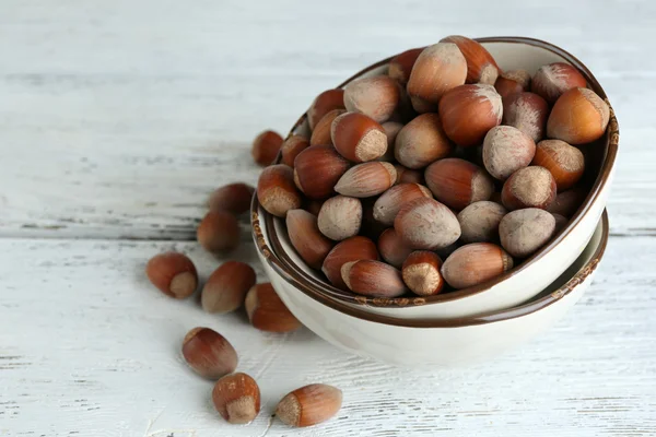 Hazelnuts in bowl on wooden background — Stock Photo, Image