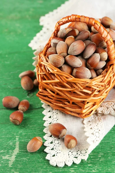 Hazelnuts in wicker basket, on napkin on wooden background — Stock Photo, Image