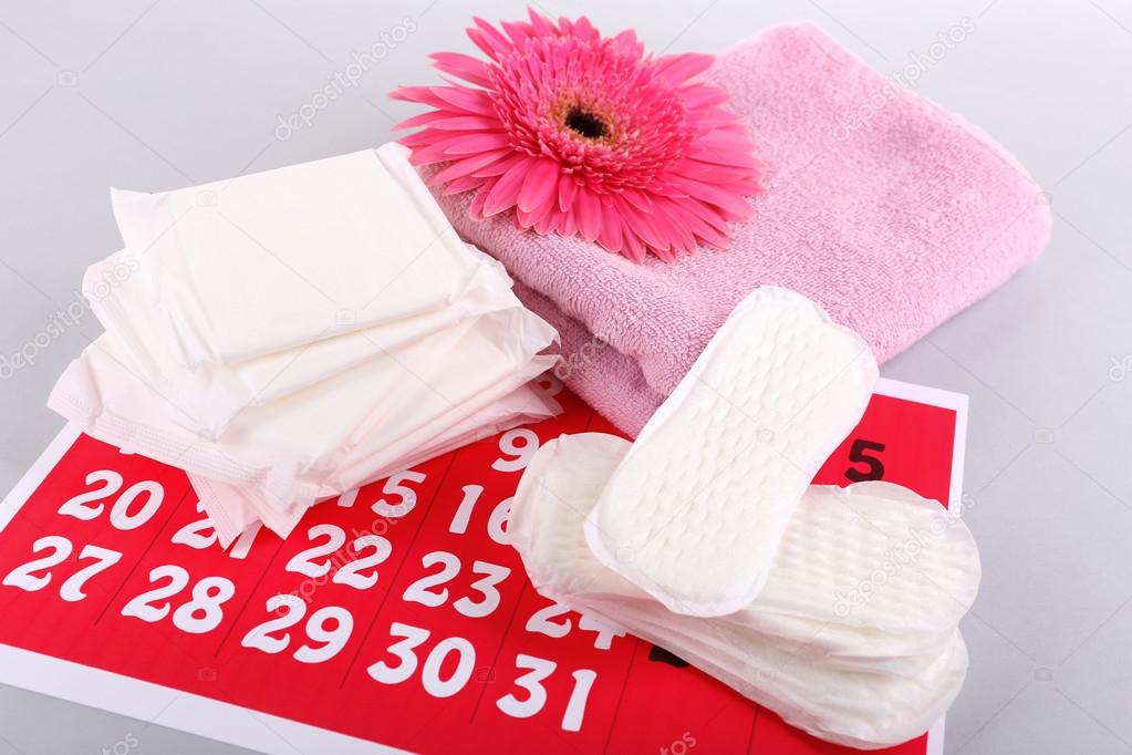 Sanitary pads, calendar, towel and pink flower on light background