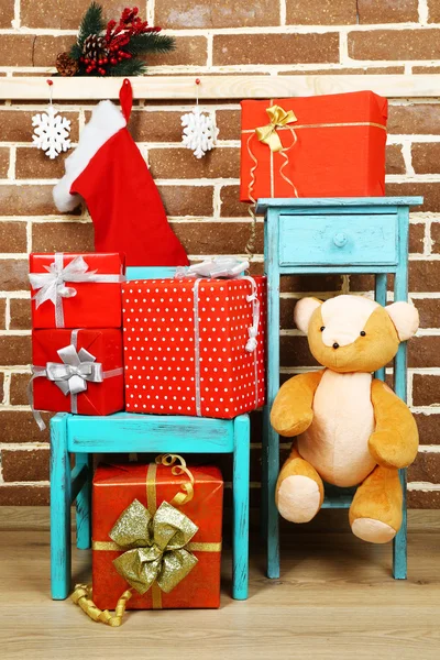 Kerstcadeautjes op stoel en boekenkast op bruin bakstenen muur achtergrond — Stockfoto