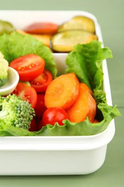 God vegetarisk mat i plastlåda på gröna träbord — Stockfoto