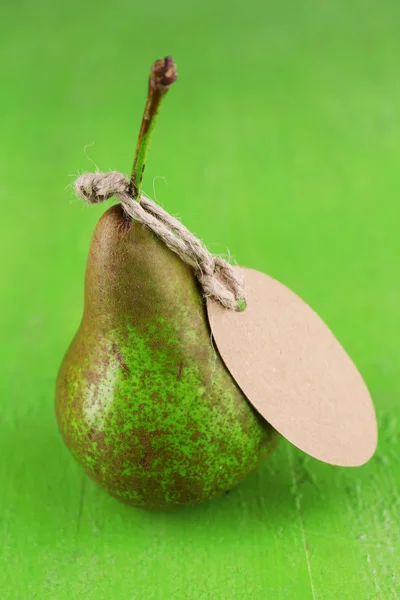 Reife Birne mit Papieranhänger auf hölzernem Hintergrund — Stockfoto