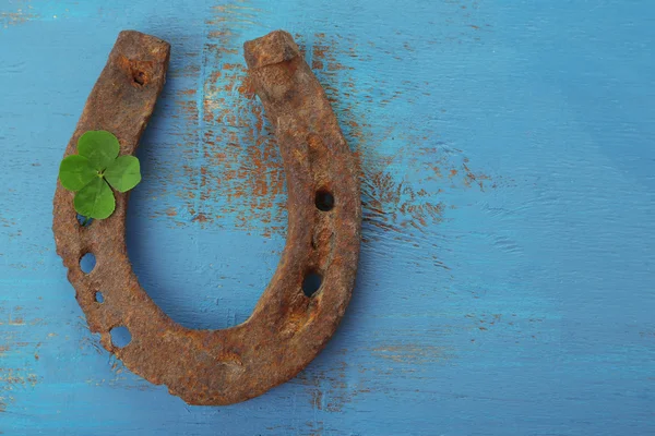 Zapato de caballo viejo, con hoja de trébol, sobre fondo de madera —  Fotos de Stock