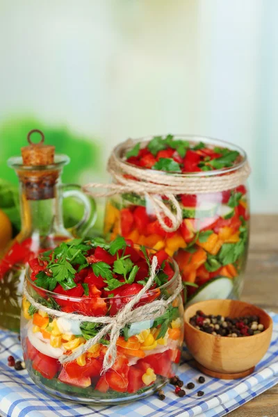 Salada de legumes em frascos de vidro na mesa de madeira, no fundo brilhante — Fotografia de Stock