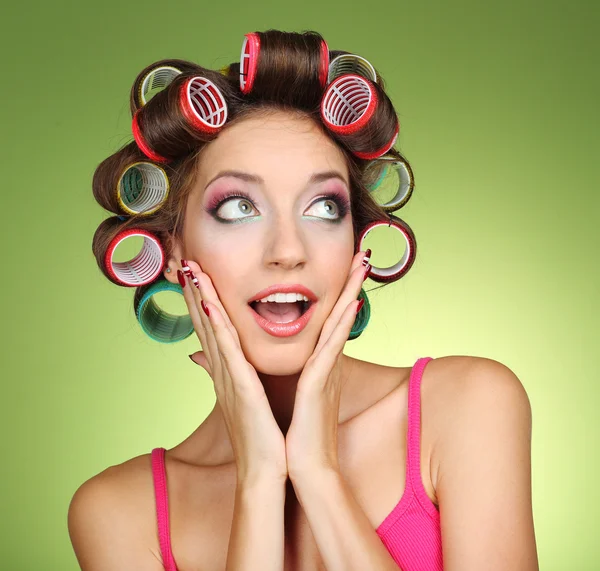 Menina bonita em encrespadores de cabelo no fundo verde — Fotografia de Stock