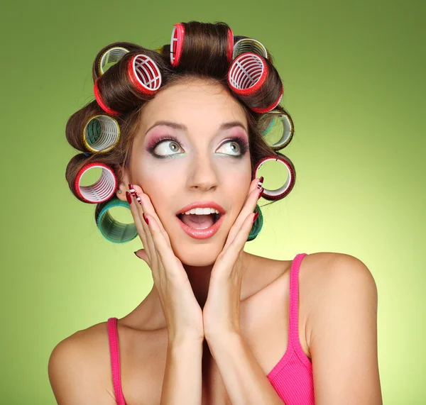 Beautiful girl in hair curlers on green background — Stock Photo, Image