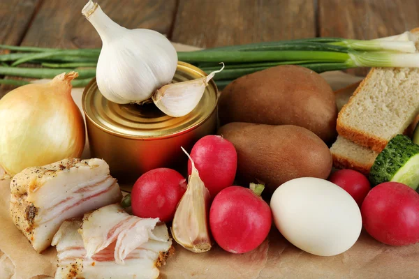 Bacon, fresh vegetables, boiled egg and bread on paper, on wooden background. Village breakfast concept. — Stock Photo, Image