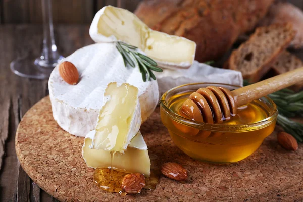 Camembert cheese, nuts, honey and bread on cutting board on wooden background — Stock Photo, Image