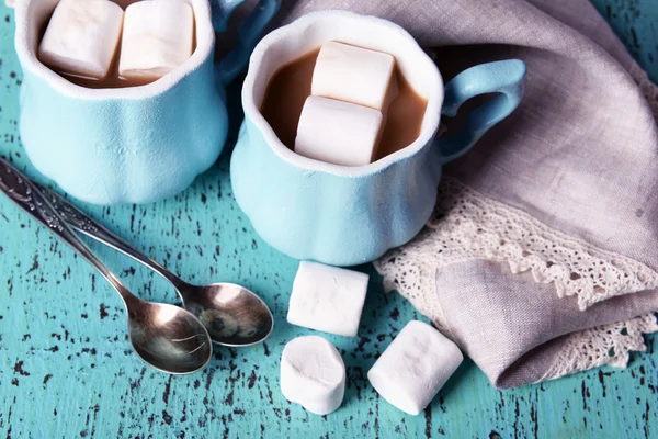 Cups of coffee with marshmallow and napkin on wooden table — Stock Photo, Image