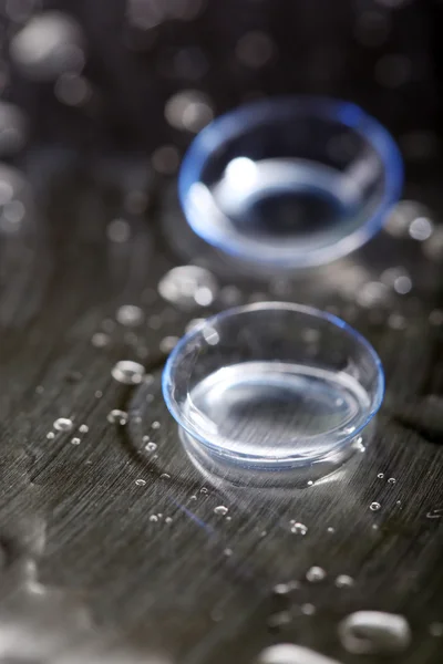 Lentes de contacto con gotas de agua sobre fondo brillante —  Fotos de Stock