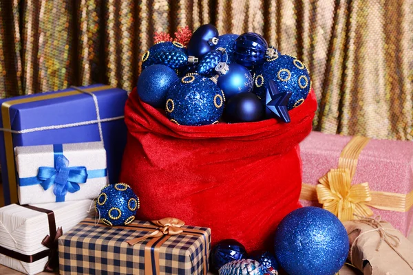 Bolso rojo con juguetes de Navidad y regalos sobre fondo de tela — Foto de Stock