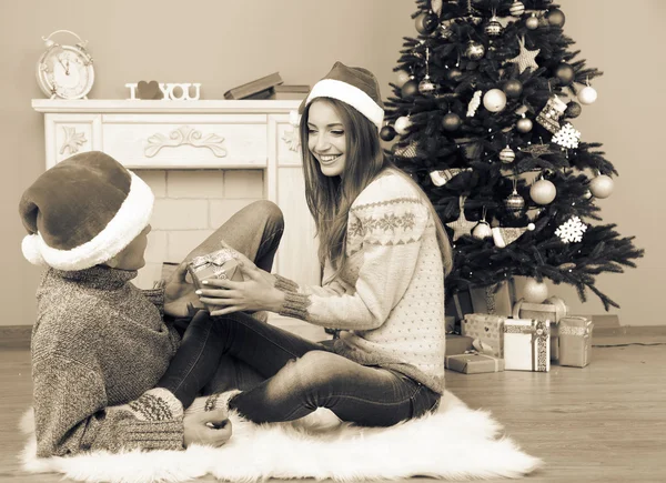 Jeune couple avec des cadeaux, assis sur le tapis, à la maison — Photo