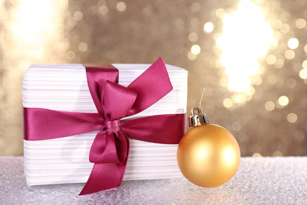 Geschenkboxen mit weinerlichen und blauen Bändern und Weihnachtsbaumspielzeug auf dem Tisch auf glänzendem Hintergrund — Stockfoto