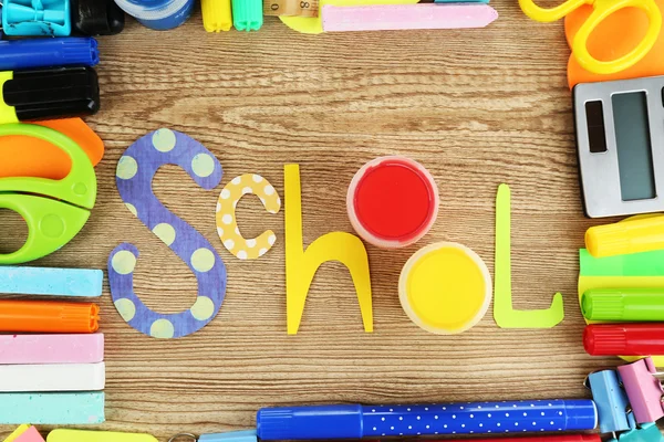 Escola de inscrição forrada de material escolar em fundo de madeira — Fotografia de Stock