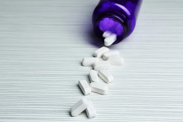 Таблетки в пляшці на білому столі — стокове фото