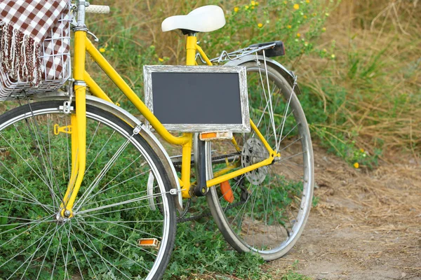 Bicicleta com quadro-negro no prado durante o pôr do sol — Fotografia de Stock