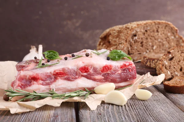 Rå bacon med bröd och kryddor på träbord — Stockfoto