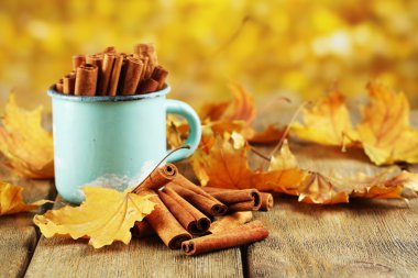 Tarçın bardağa sarı yaprakları ile sopa.