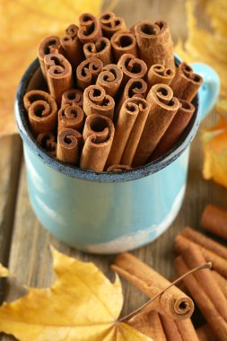 Tarçın bardağa sarı yaprakları ile sopa.