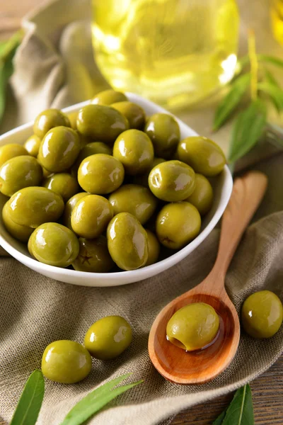 Groene olijven in kom met bladeren — Stockfoto