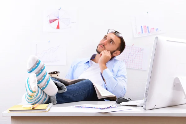 Businessman holding his legs on desk — Stock Photo, Image