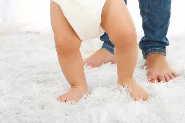 Schattige babyjongen eerste stappen met moeder in kamer — Stockfoto
