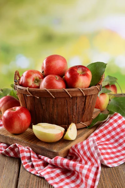 Manzanas dulces en canasta de madera sobre mesa sobre fondo brillante — Foto de Stock