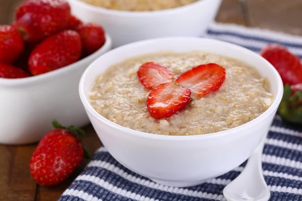 Tasty oatmeal with strawberries on table close-up — Stock Photo, Image