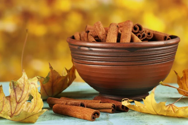 Varas de canela em tigela com folhas amarelas — Fotografia de Stock