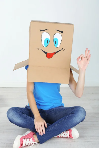 Woman with cardboard box on her head with happy face — Stock Photo, Image