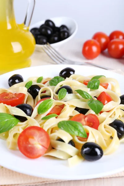 Espaguetis con tomates, aceitunas, aceite de oliva y hojas de albahaca — Foto de Stock