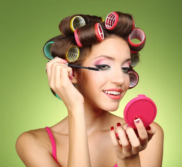 Beautiful girl in hair curlers on green background — Stock Photo, Image