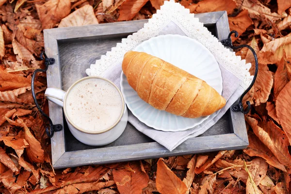 Beker van lekkere warme drank en verse croissants — Stockfoto