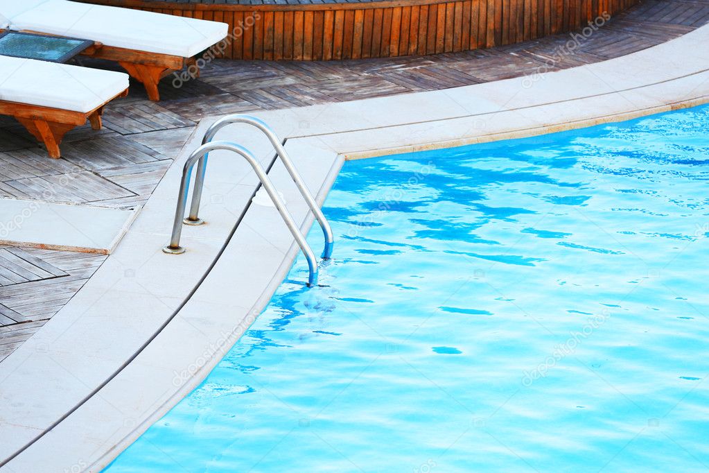 Lounge sunbeds near swimming pool Stock Photo by ©belchonock 56880149