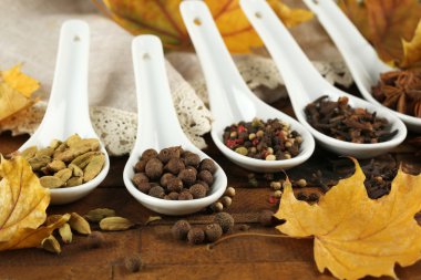 Sarı yapraklar kaşıklarla içinde farklı baharatlar